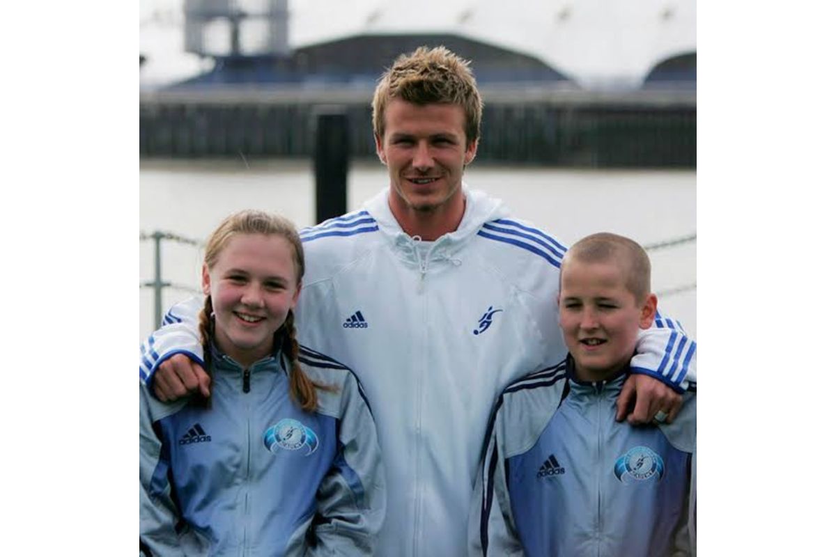 Foto colorida de homem ao lado de um menino e uma menina com uniforme de escola de futebol - Metrópoles