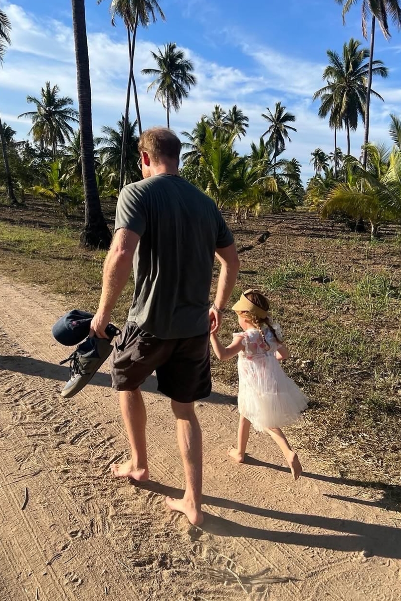 Foto colorida de homem e menina de mãos dadas. Eles estão andando descalços - Metrópoles